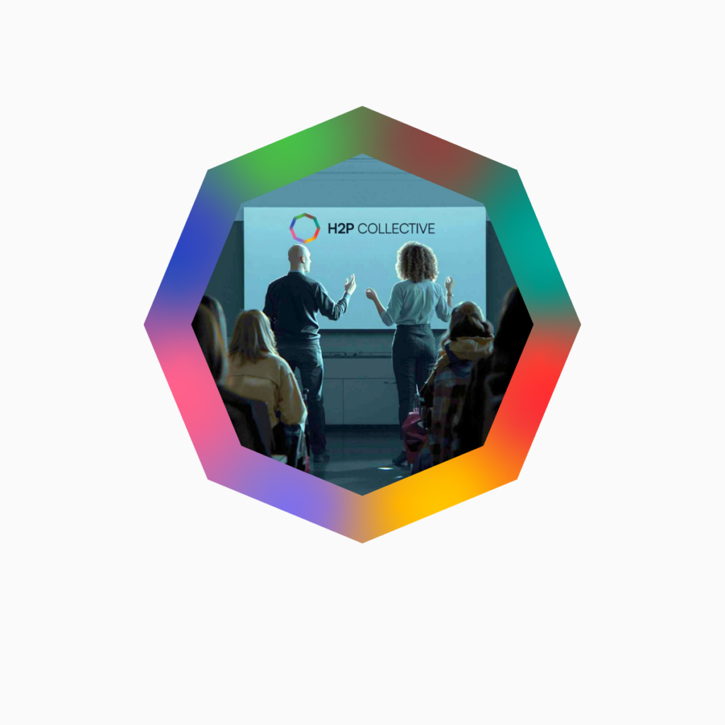 Two facilitators presenting to a seated audience with H2P Collective logo displayed on screen, framed within an octagonal border with gradient colors representing the eight pillars.